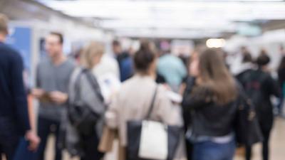 Verschwommene Aufnahme von Menschen auf einer Messe. 