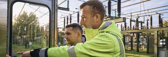 Transformator Strom Anlage mit zwei Mitarbeitenden