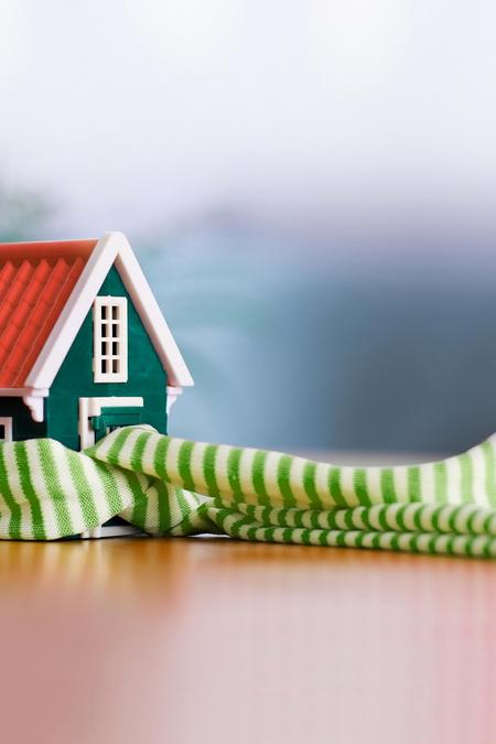 Kleines Haus mit einem grün-weißen Schal Wärme Heizung