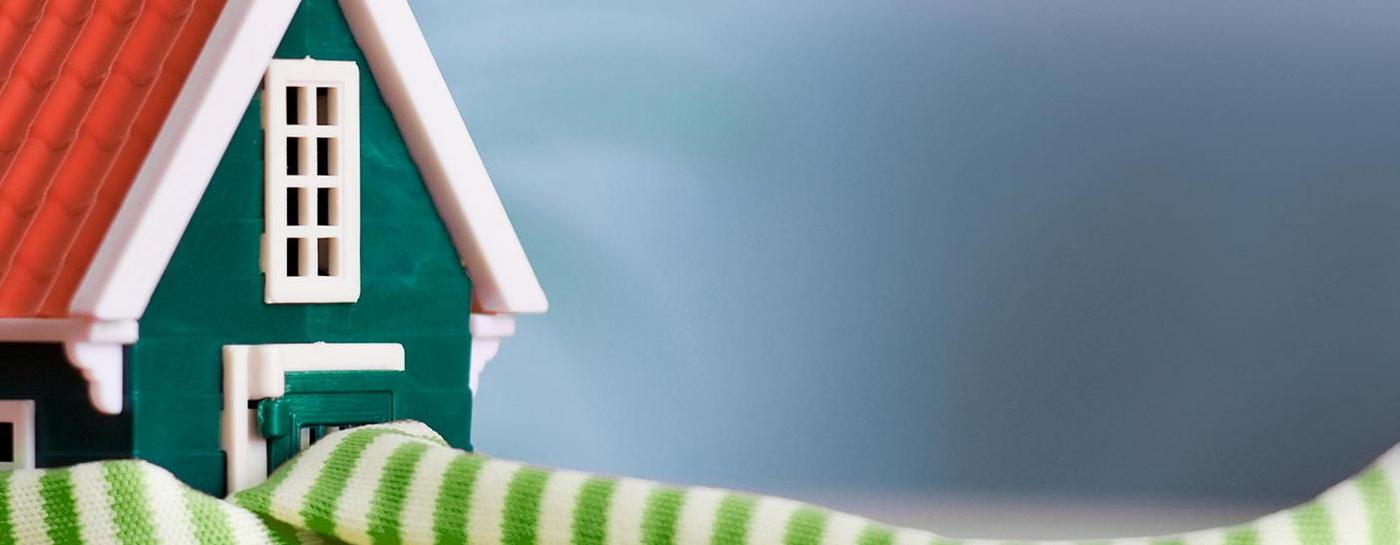 Kleines Haus mit einem grün-weißen Schal Wärme Heizung