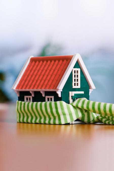 Kleines Haus mit einem grün-weißen Schal Wärme Heizung