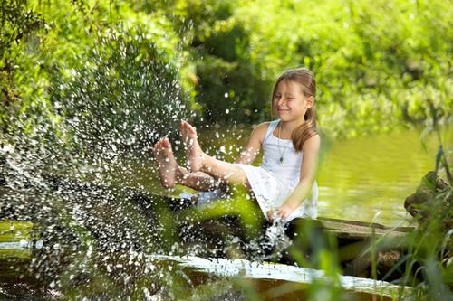 Mädchen spielt mit Wasser an einem Bach im Wald.