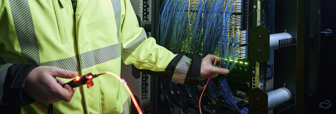 Mitarbeiter arbeitet an Glasfasertechnik in einem POP von Stadtwerke Flensburg