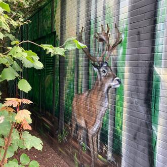 Bunt bemaltes Steinhäuschen mit einem Hirsch.
