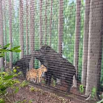 Bunt bemalte Wand mit zwei Wildschweinen mit Frischlingen sowie Bäumen.