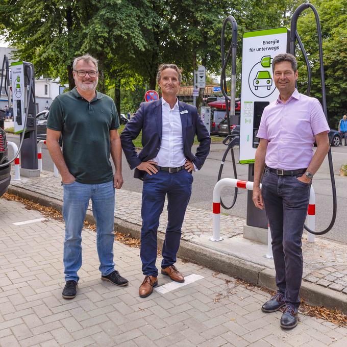 Drei Männer stehen an einer Ladestation der Stadtwerke Flensburg.