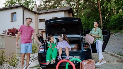 Familie lädt E-Auto an der Ladesäule vor dem Ferienhaus