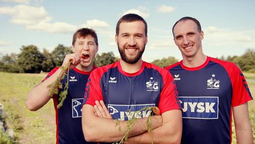Drei Spieler der Handballmannschaft SG Flensburg-Handewitt stehen in Trikots auf einem Feld