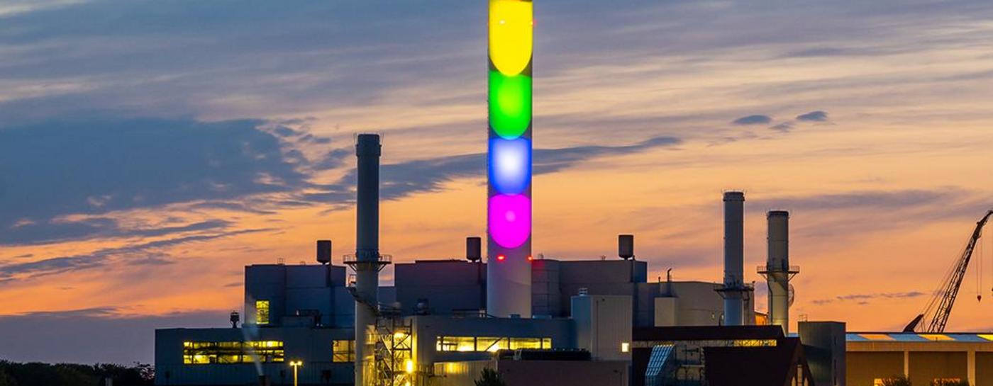 Stadtwerke Flensburg Schornstein in Regenbogenfarben beleuchtet bei Dämmerung. Diversity.