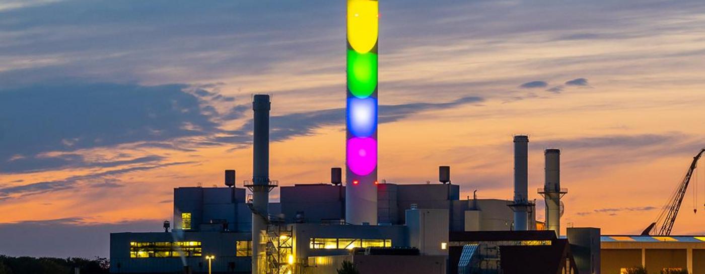 Stadtwerke Flensburg Schornstein in Regenbogenfarben beleuchtet bei Dämmerung. Diversity.