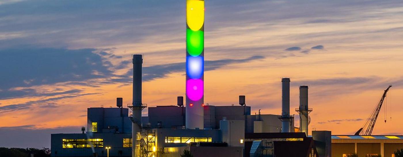 Stadtwerke Flensburg Schornstein in Regenbogenfarben beleuchtet bei Dämmerung. Diversity.