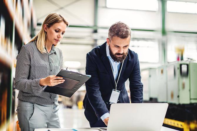 Gewerbetarif: zwei Mitarbeiter arbeiten gemeinsam am Computer im Lager