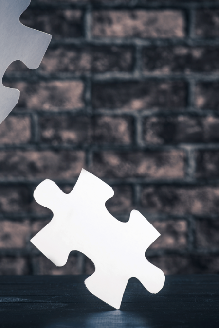 Puzzleteile auf einer dunklen Backsteinwand.