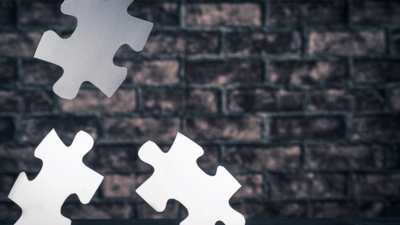 Puzzleteile auf einer dunklen Backsteinwand.