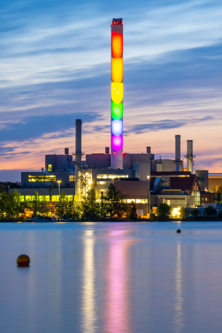 Kraftwerk Schornstein beleuchtet in Regenbogen Farben