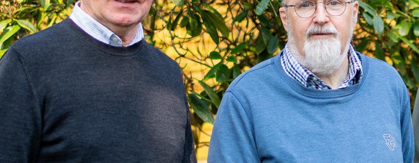 Drei Wasserturmbetreuer stehen vor einem grünem Busch