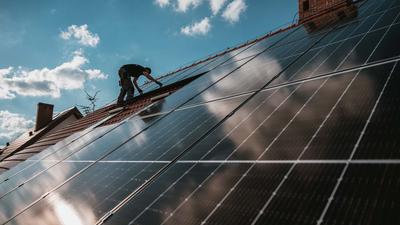 Solarzellen glänzen auf einem Hausdach.