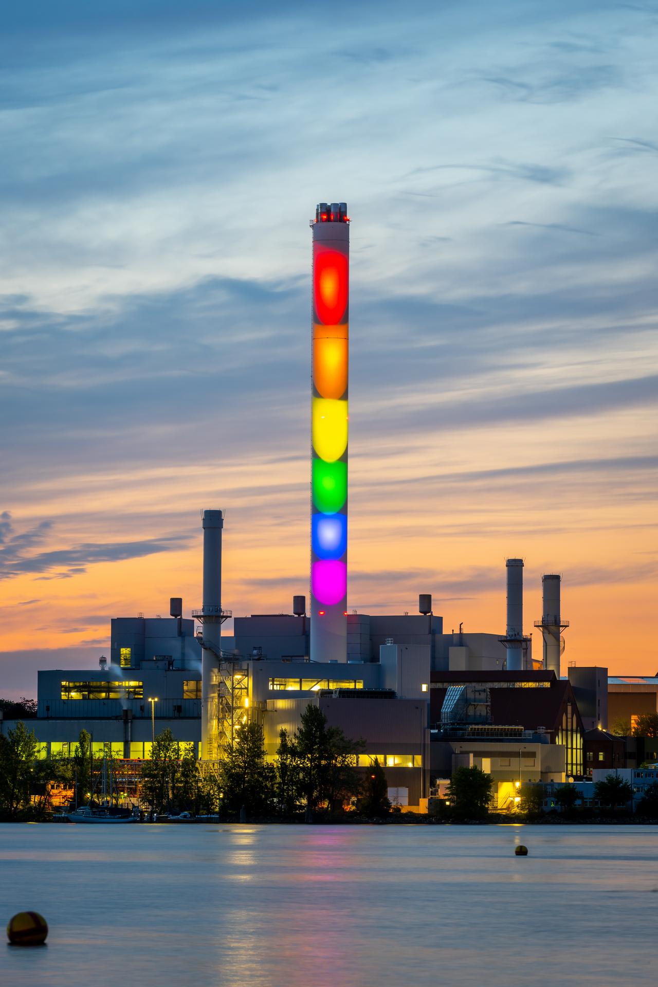 Stadtwerke Flensburg Schornstein im Hochformat in Regenbogenfarben beleuchtet bei Dämmerung, Diversity.