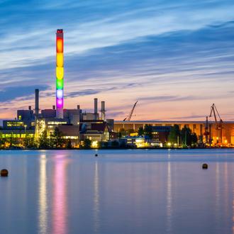 Der Schornstein der Stadtwerke Flensburg leuchtet in Regenbogenfarben bei Dämmerung.